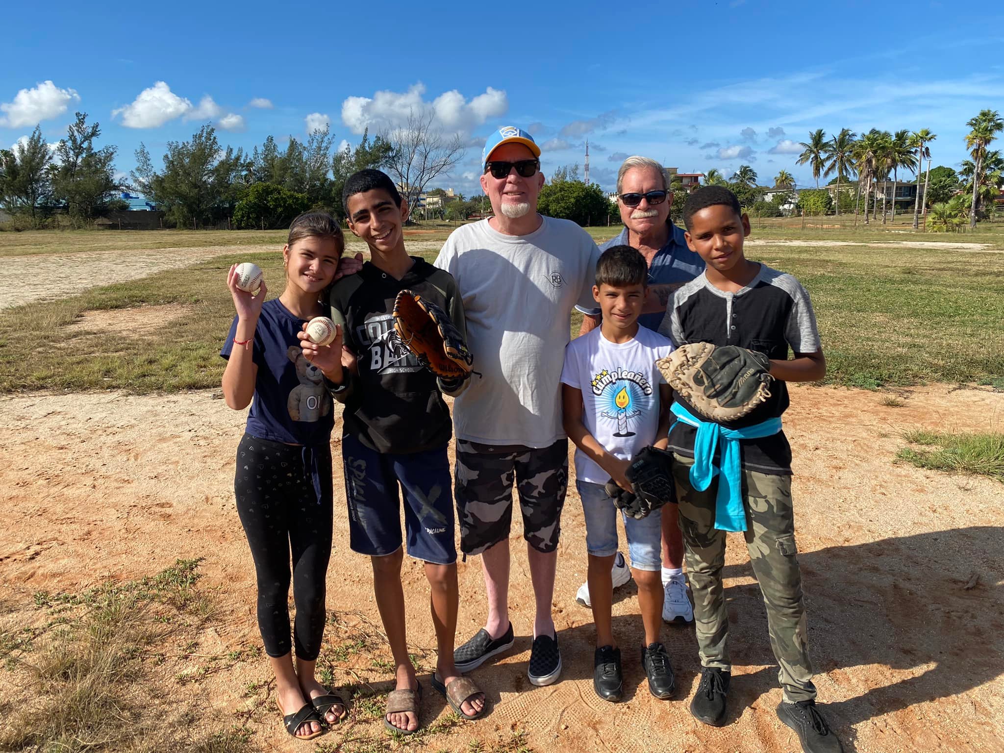 A photo of John Parsons, founder of Gloves for Cuba, and children with baseball equipment.