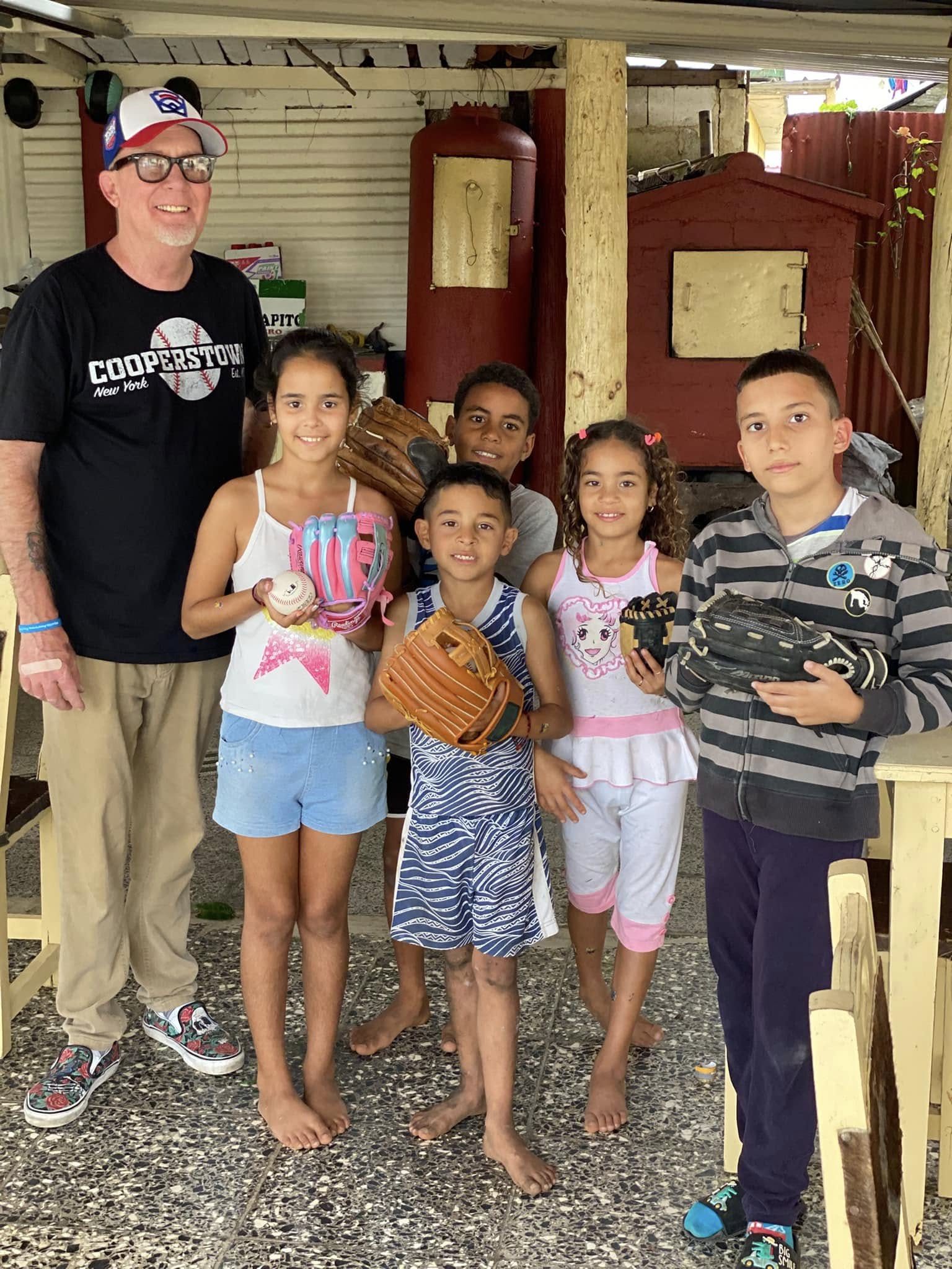 A photo of John Parsons, founder of Gloves for Cuba, and children with baseball equipment.