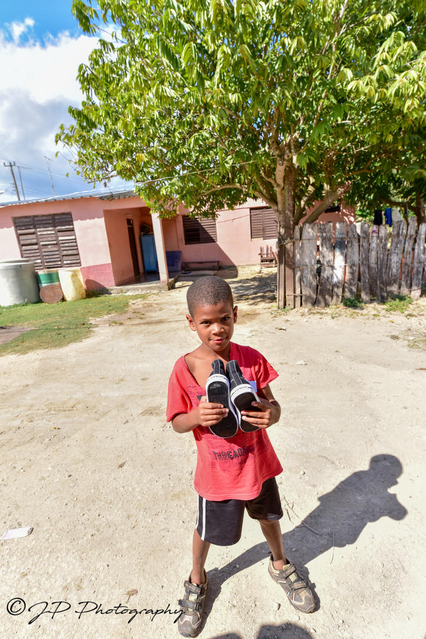 Cuban youth holding donated baseball shoes.